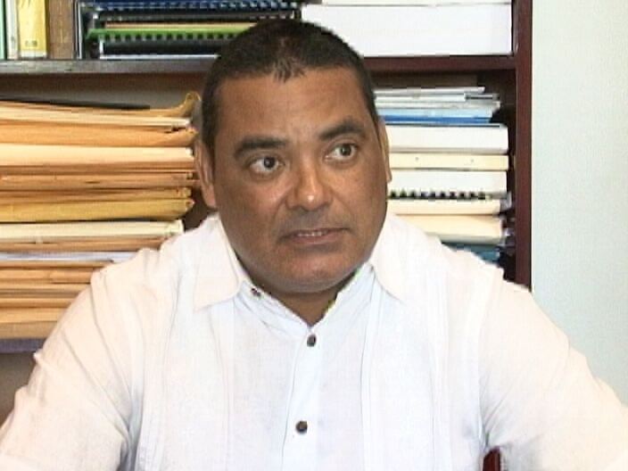 Francis Fonseca seated at a desk in front of shelves of files and law reports during an interview.