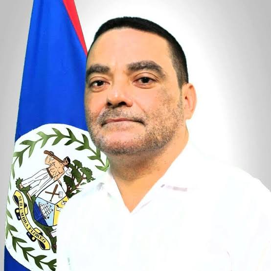Portrait of Francis Fonseca in a white shirt against the flag of Belize.
