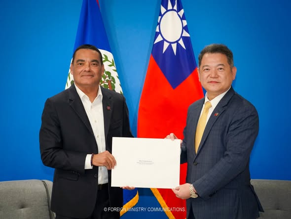 Francis Fonseca and a representative jointly holding a white document envelope before the flags of Belize and the Republic of China (Taiwan).